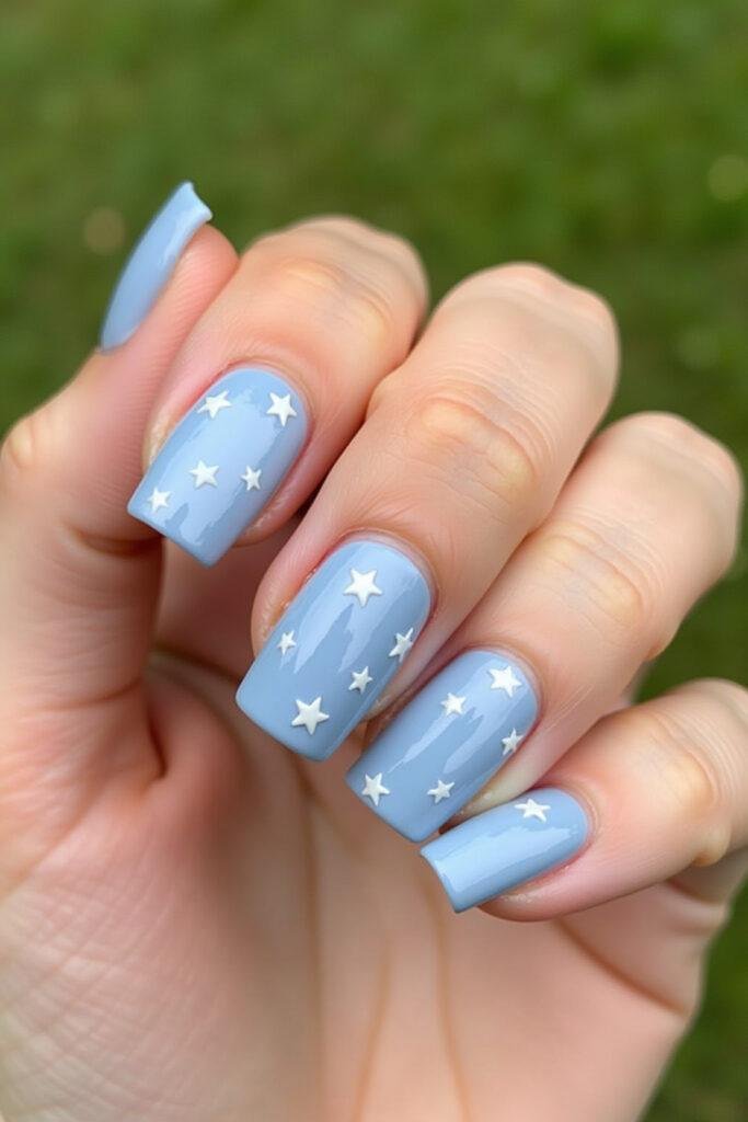 Close-up of a manicured hand showcasing light blue nails with various cute designs.