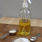 Homemade magnesium oil spray in a glass bottle with magnesium flakes and a measuring spoon on a wooden table