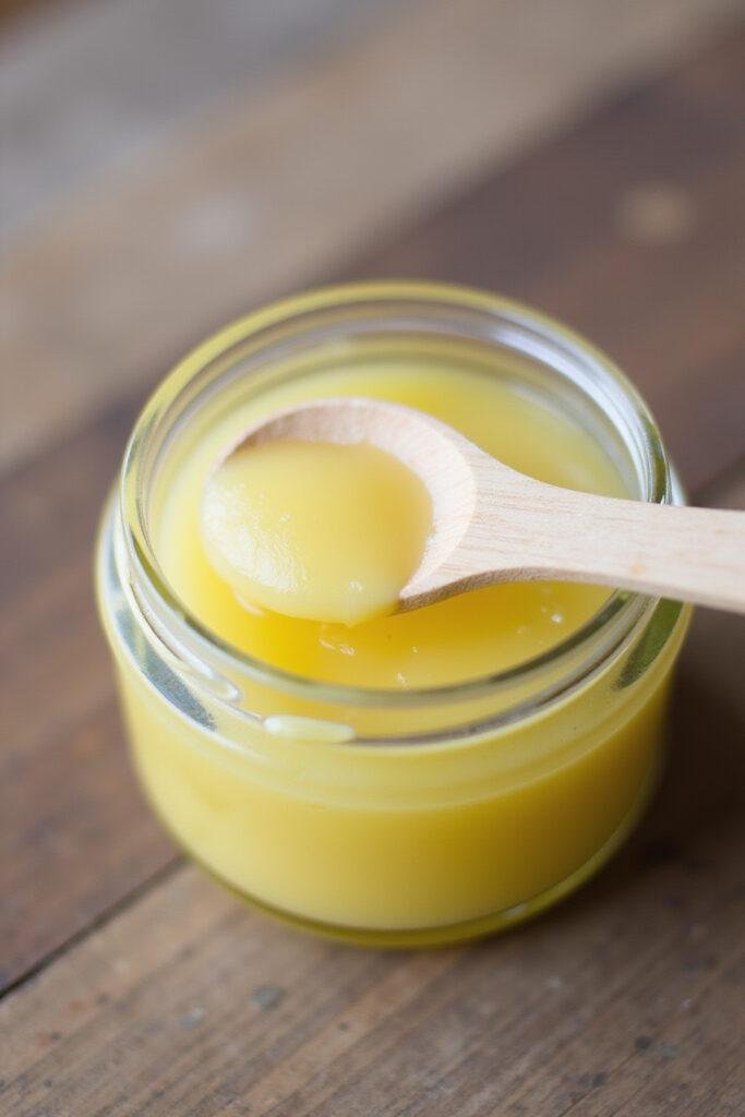 Homemade allergy relief balm in a glass jar with a wooden spoon on a wooden surface
