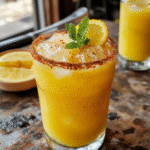 A vibrant glass of Festive Spiced Margarita featuring a salted rim, adorned with a cinnamon stick and orange slice, vibrant red and orange colors, with a cozy holiday backdrop, textured surface, and freshly sliced citrus visible.